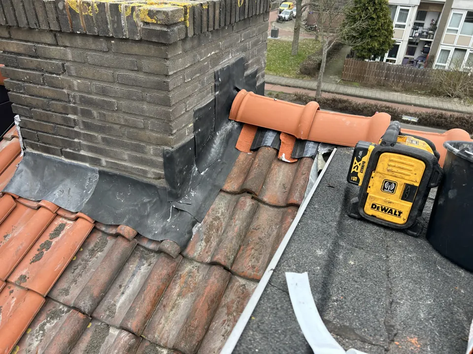 Loodvervanging rond een schoorsteen, in uitvoering met gereedschap op het pannendak
